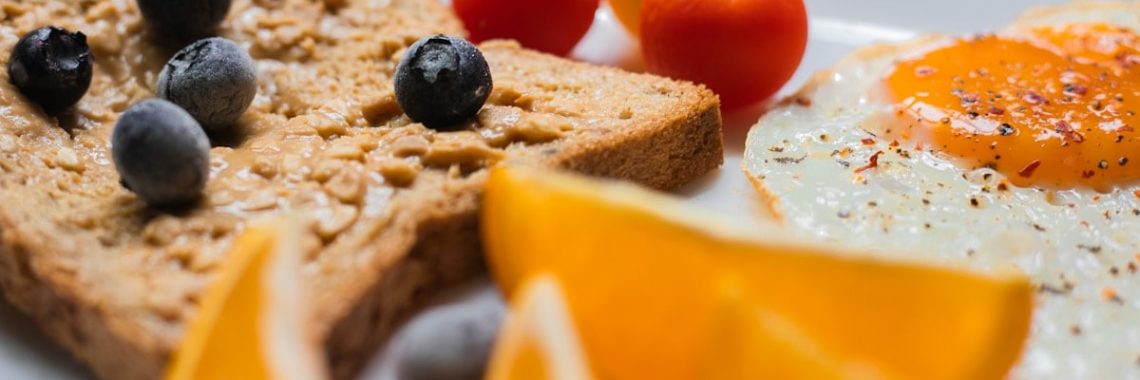 sliced bread with sliced orange and blue berries on white ceramic plate